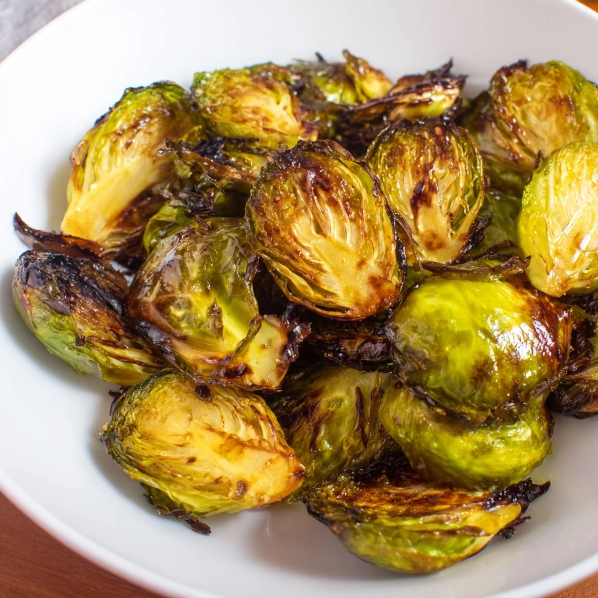 Roasted Brussels sprouts with balsamic glaze, served warm alongside roasted chicken, their caramelized edges glowing in soft natural light.