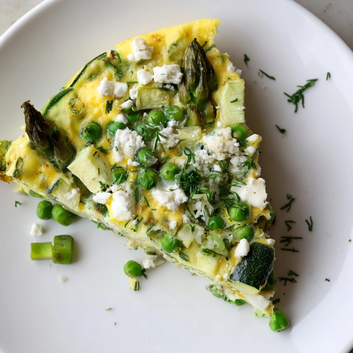 Golden-baked spring vegetable frittata with herbs, featuring tender zucchini and scallions, sliced for an easy vegetarian dinner.