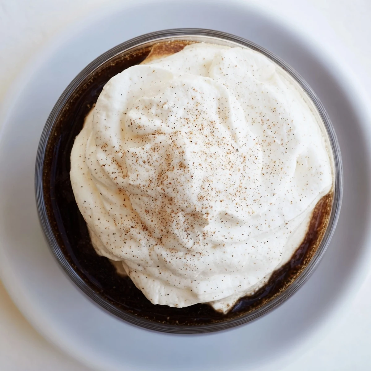 A close-up of an Irish Coffee Mocktail with Whipped Cream, featuring rich brown sugar coffee topped with fluffy vanilla-scented cream and a dusting of nutmeg.