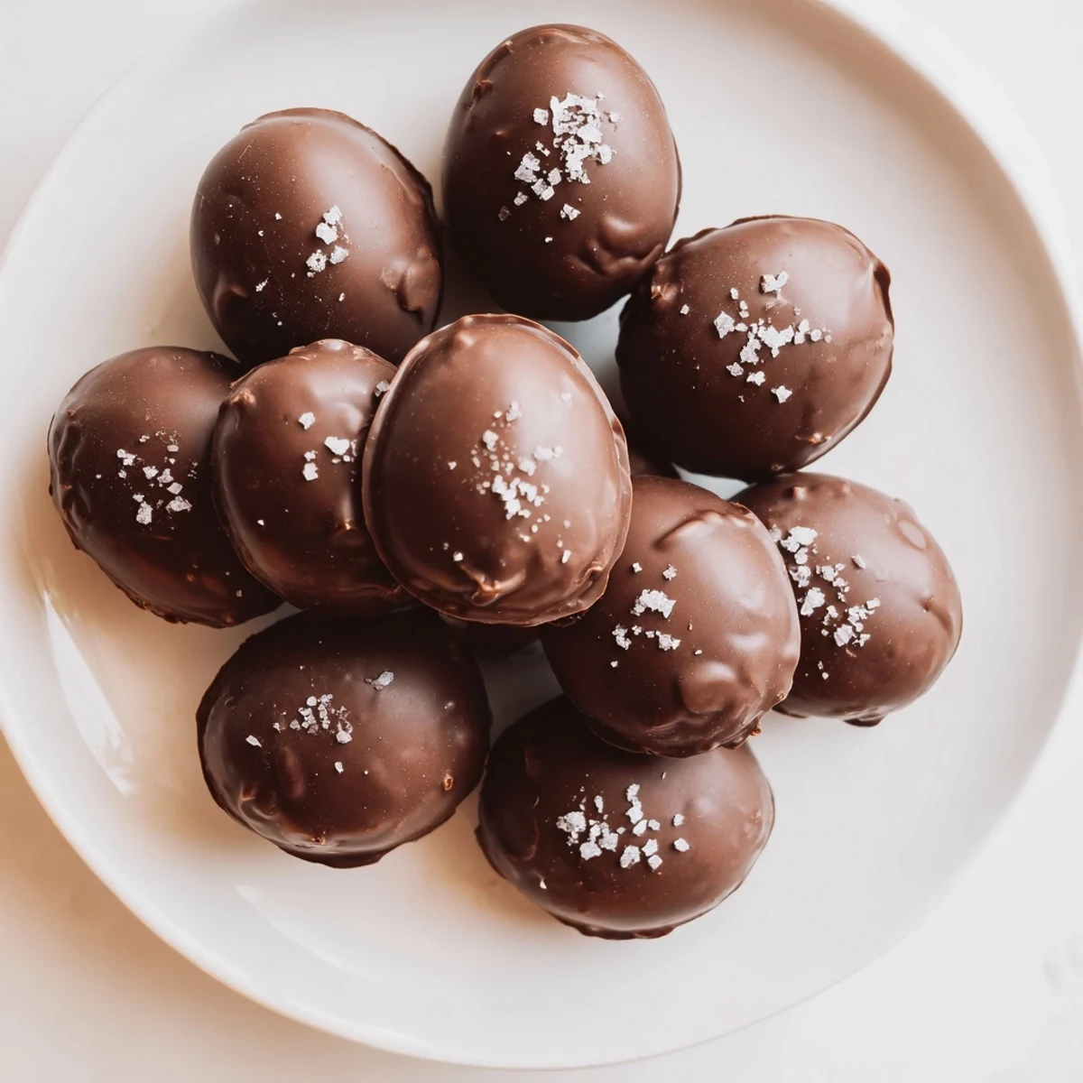Stacked Chocolate Peanut Butter Eggs with Sea Salt arranged on a dessert plate near a steaming mug of coffee, ready for a sweet afternoon snack.