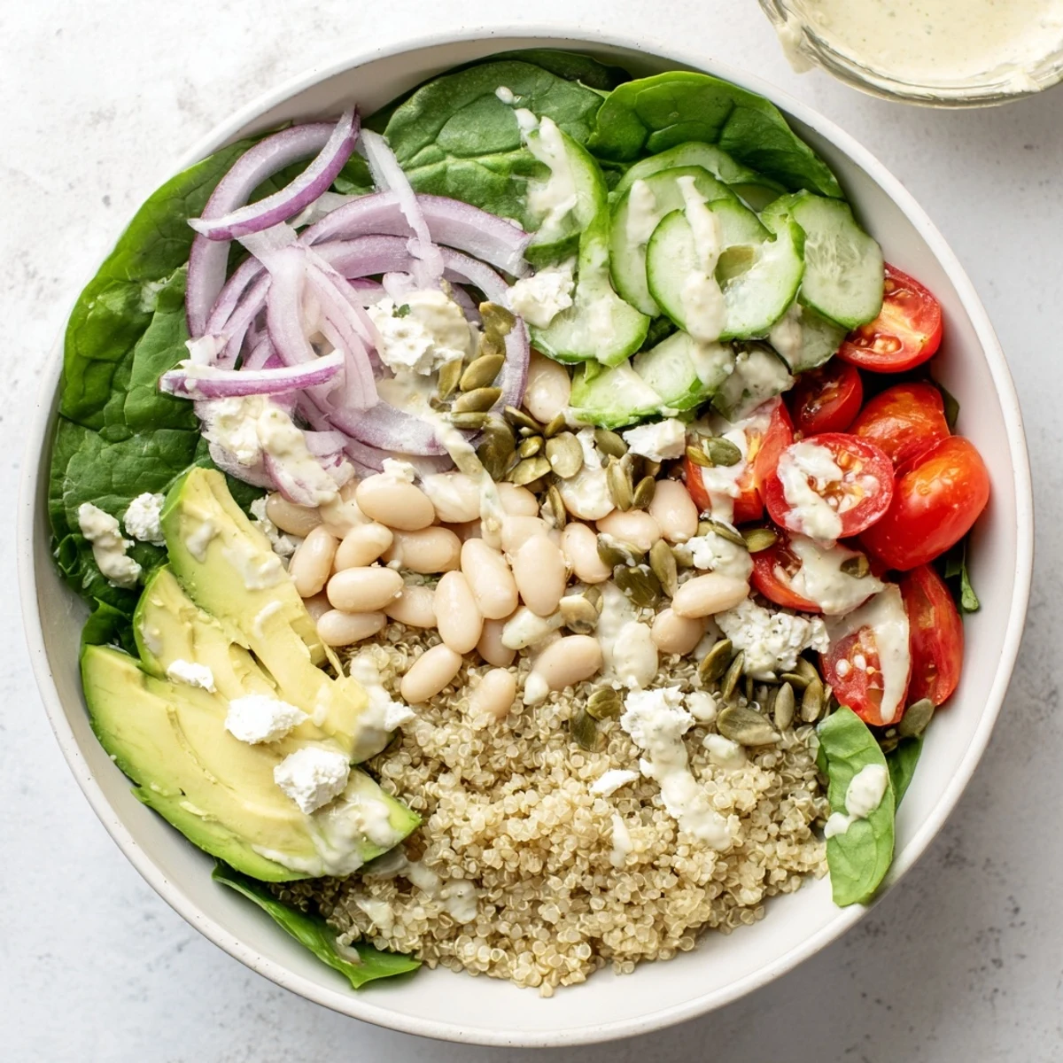 A vibrant Spinach & White Bean Ultimate Protein Power Bowl topped with creamy avocado and feta.