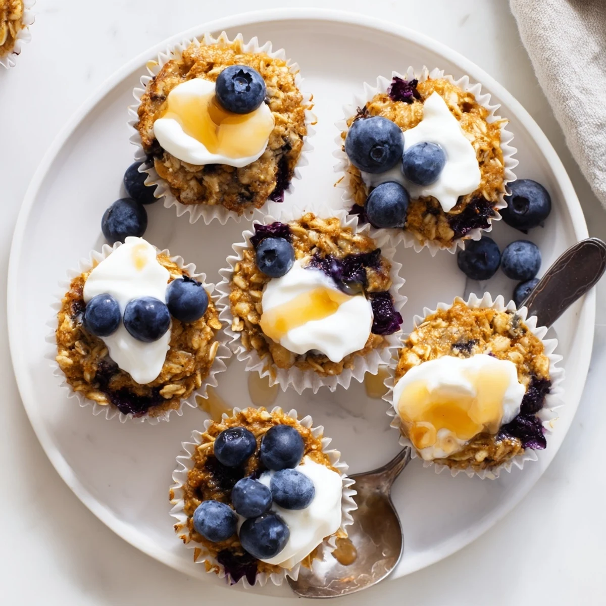 These moist Baked Oatmeal Cups with Greek Yogurt are arranged in a muffin tin with a dollop of Greek yogurt topping.