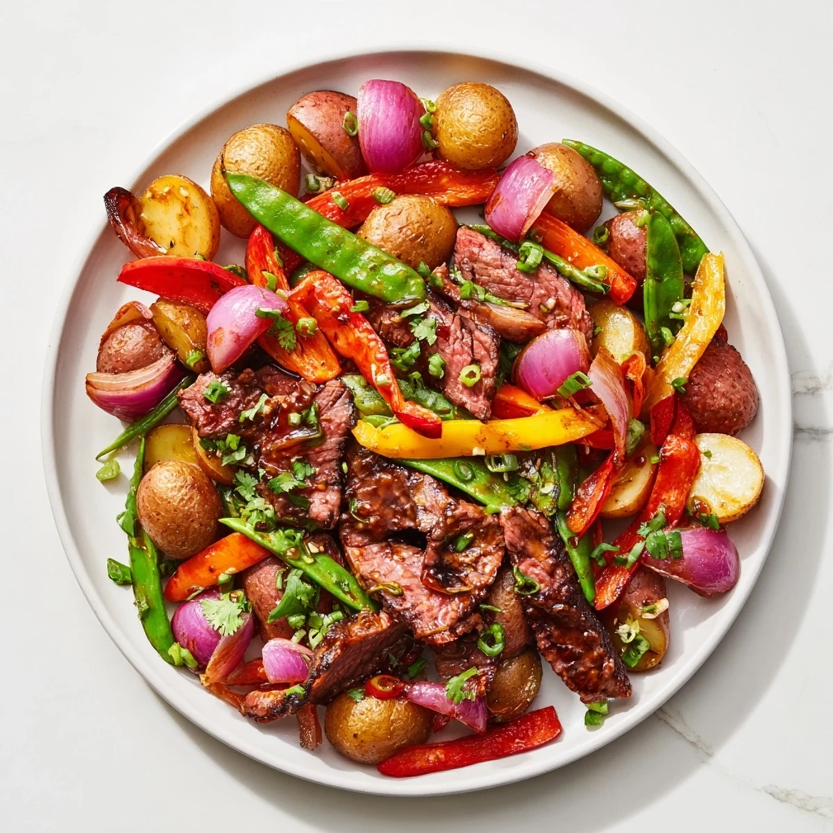 Sizzling Blackstone Cowboy Stir Fry Dinner with beef, peppers, and potatoes on a griddle.