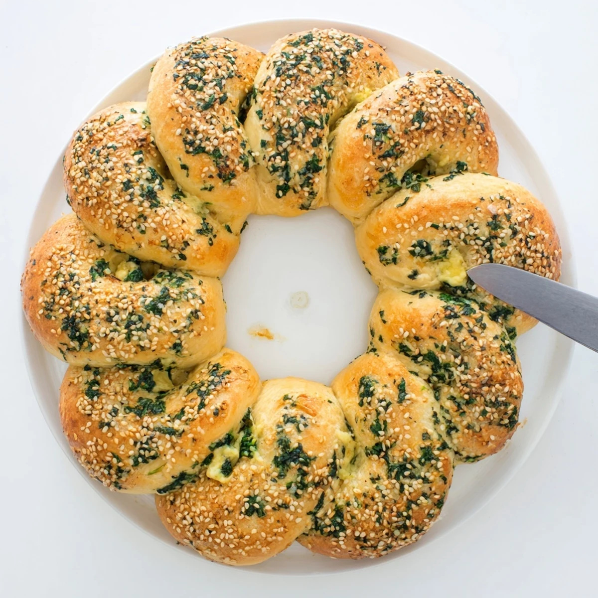 Freshly baked Spinach Cottage Cheese Flagels on a wooden board, golden-brown and studded with sesame seeds.