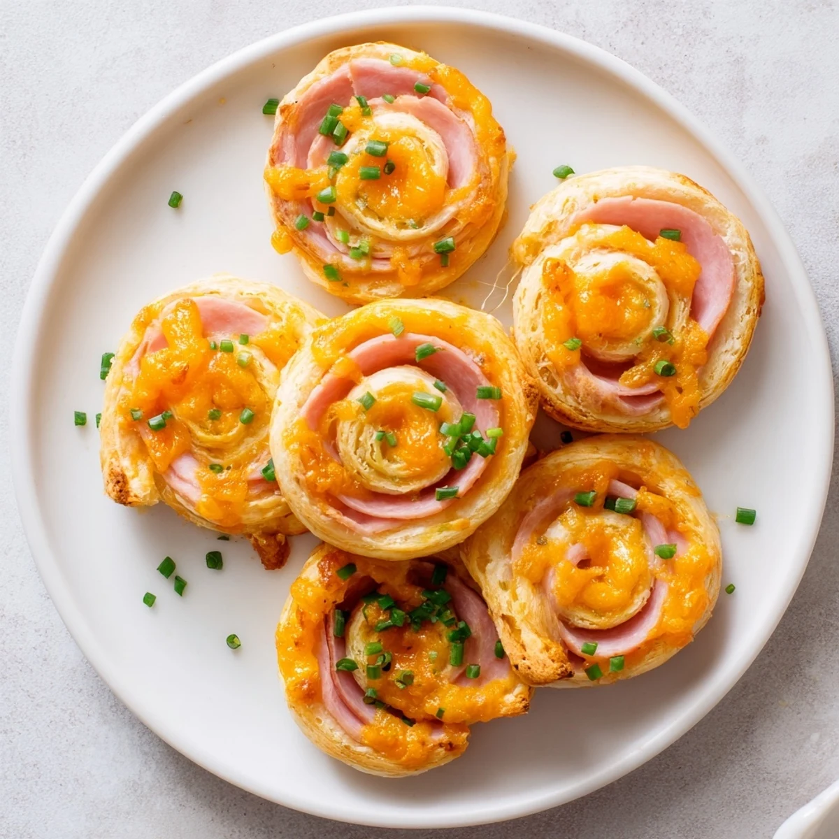 Baked Easter Ham Cheddar Pinwheels arranged on a wooden board, showcasing their golden pastry layers and savory ham and cheddar cheese filling