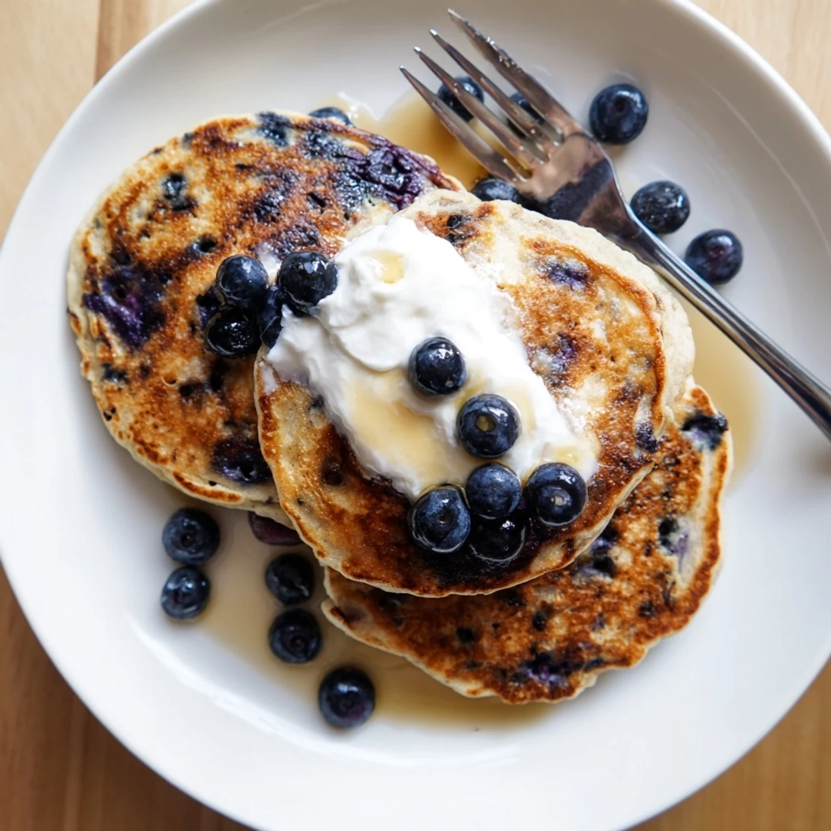 Breakfast plate serving tangy Greek yogurt blueberry pancakes with melted butter and powdered sugar