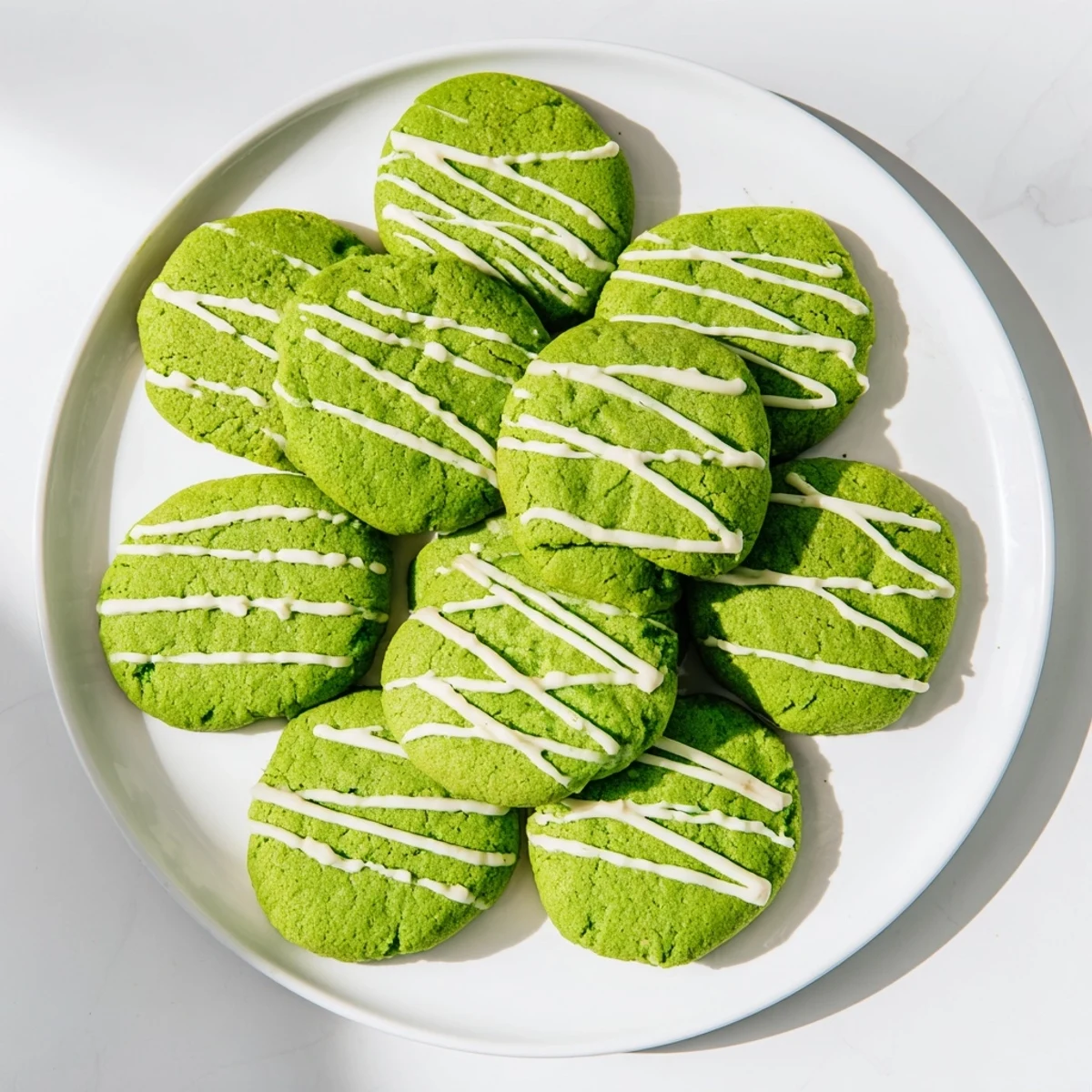 Vibrant green cookies with sweet white chocolate swirls arranged on a baking sheet.