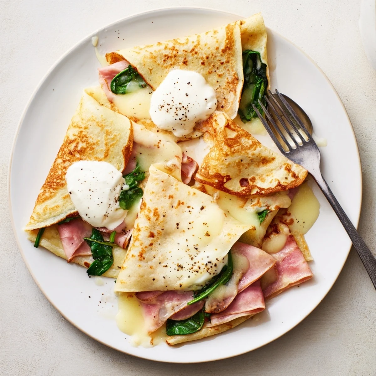 Golden savory crepes filled with melted Gruyère cheese, ham, and fresh spinach