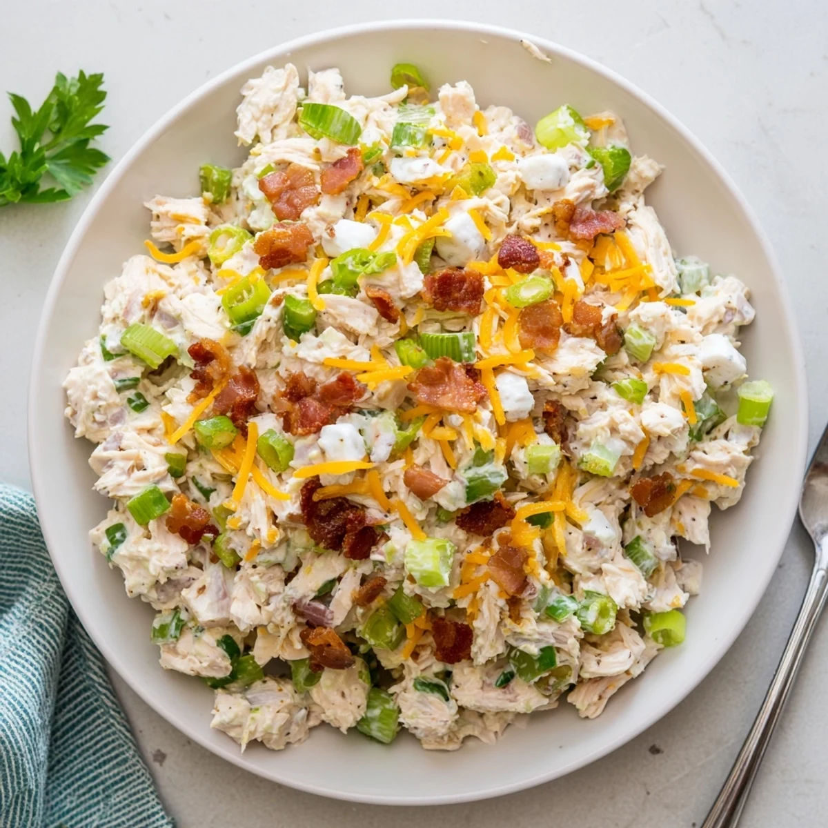 Creamy low carb jalapeno popper cottage cheese chicken salad served in a white bowl topped with crispy bacon bits and fresh green onions