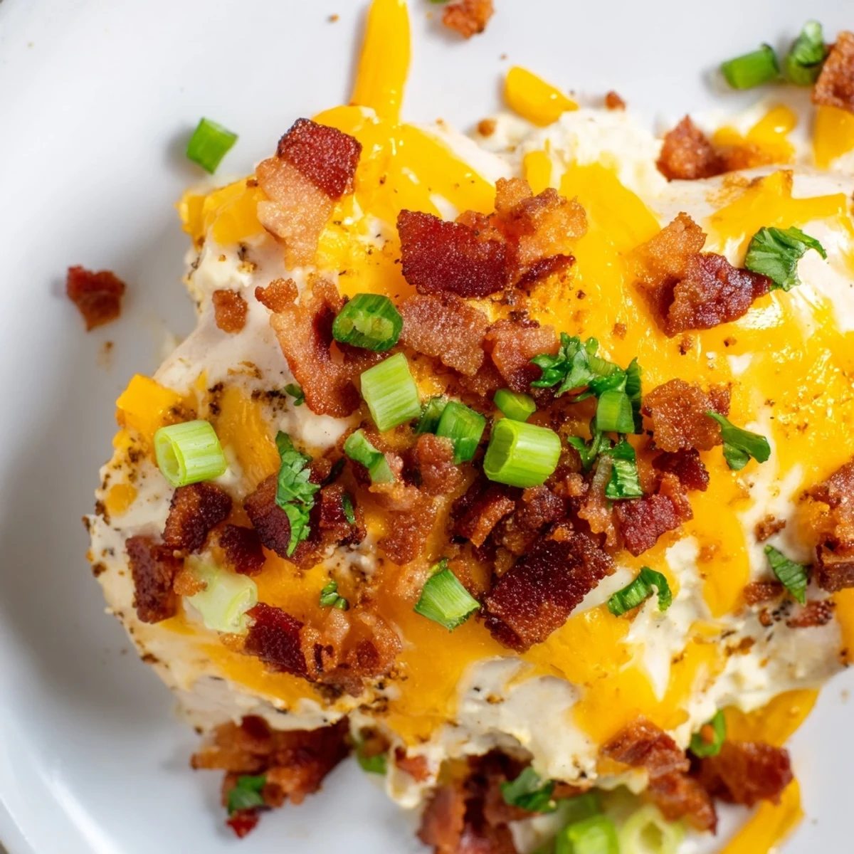 Juicy baked chicken smothered in cream cheese ranch sauce topped with bacon and green onion garnish