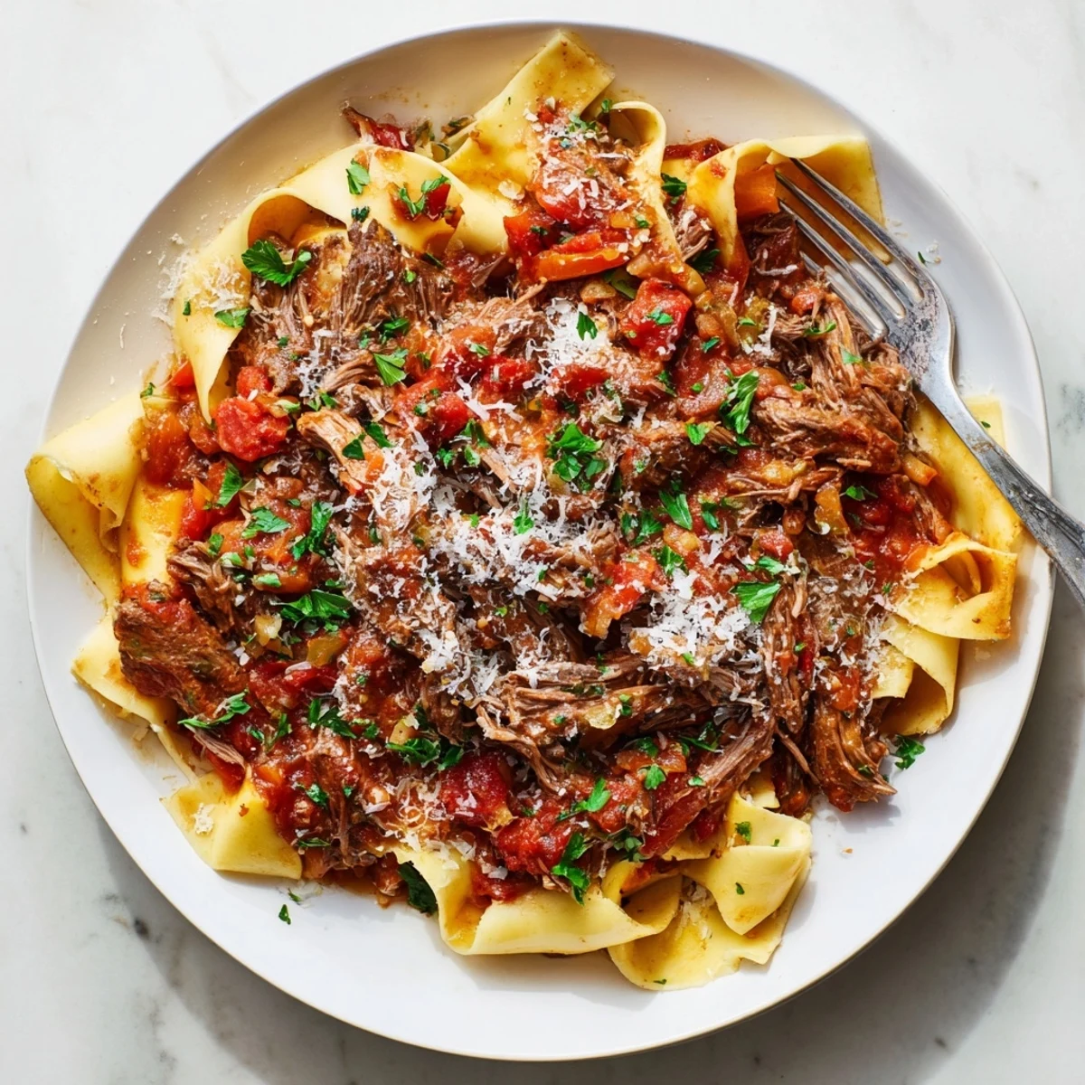 Creamy slow cooker beef ragu served over polenta with fresh parsley and grated Parmesan cheese