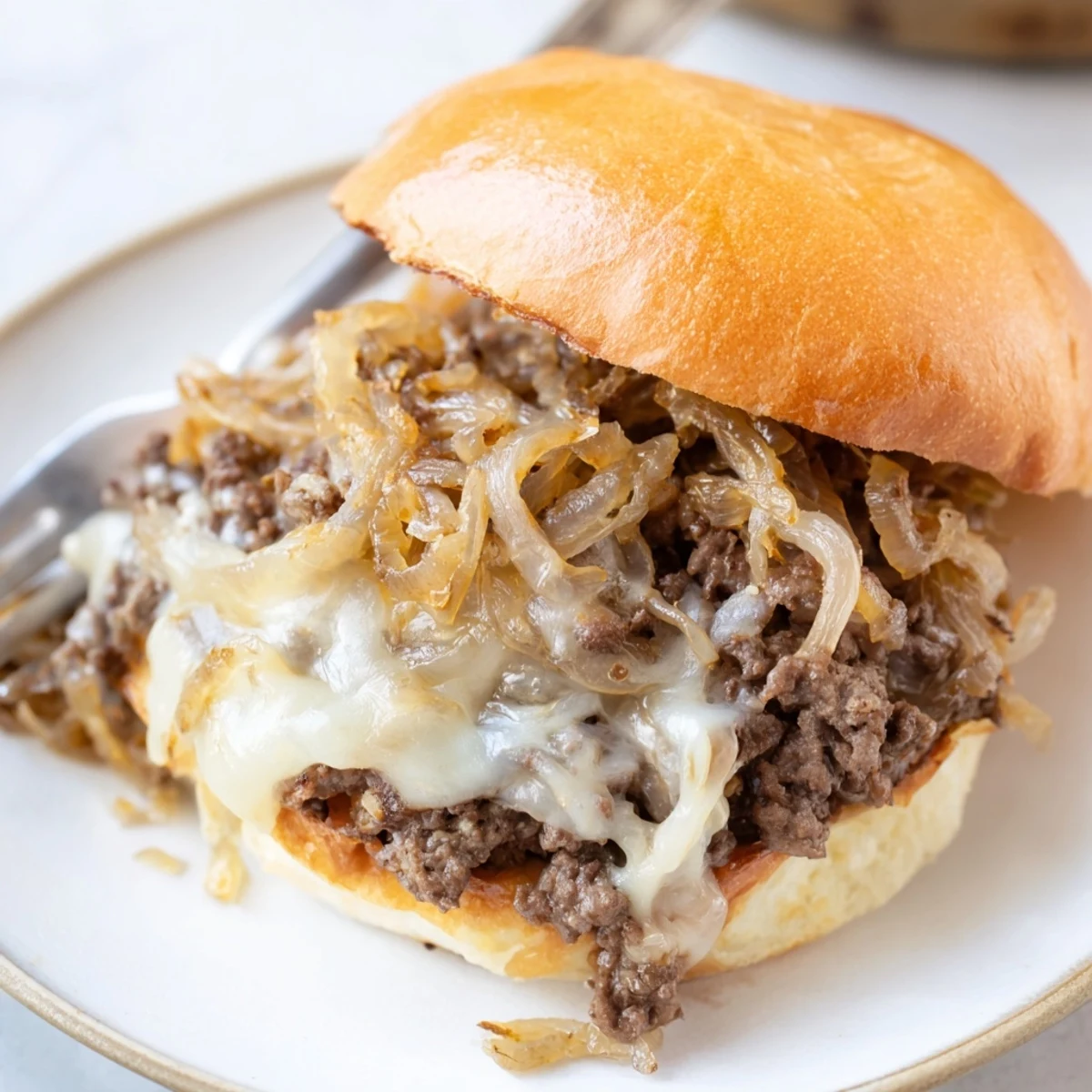 Hearty sloppy joe sandwich topped with golden bubbly cheese and sweet caramelized onion beef filling