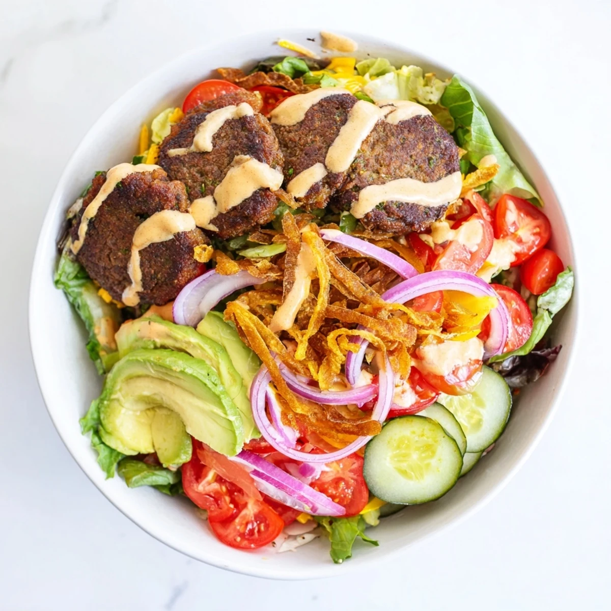 Colorful low-carb smash burger bowl featuring juicy beef, avocado, tomatoes, and tangy homemade special sauce drizzled on top