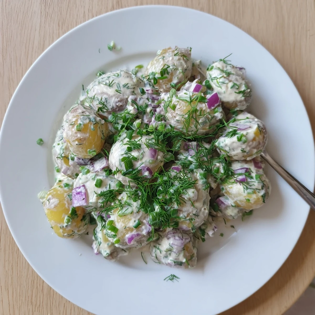 Light and tangy Greek yogurt potato salad featuring celery, dill, and parsley in a bowl