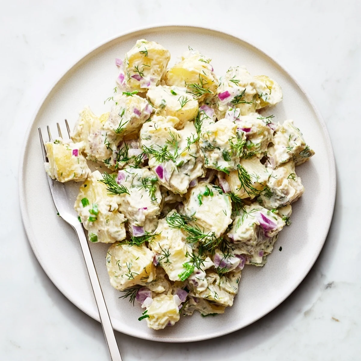 Creamy Greek yogurt potato salad with tender potatoes, fresh herbs, and crunchy red onion