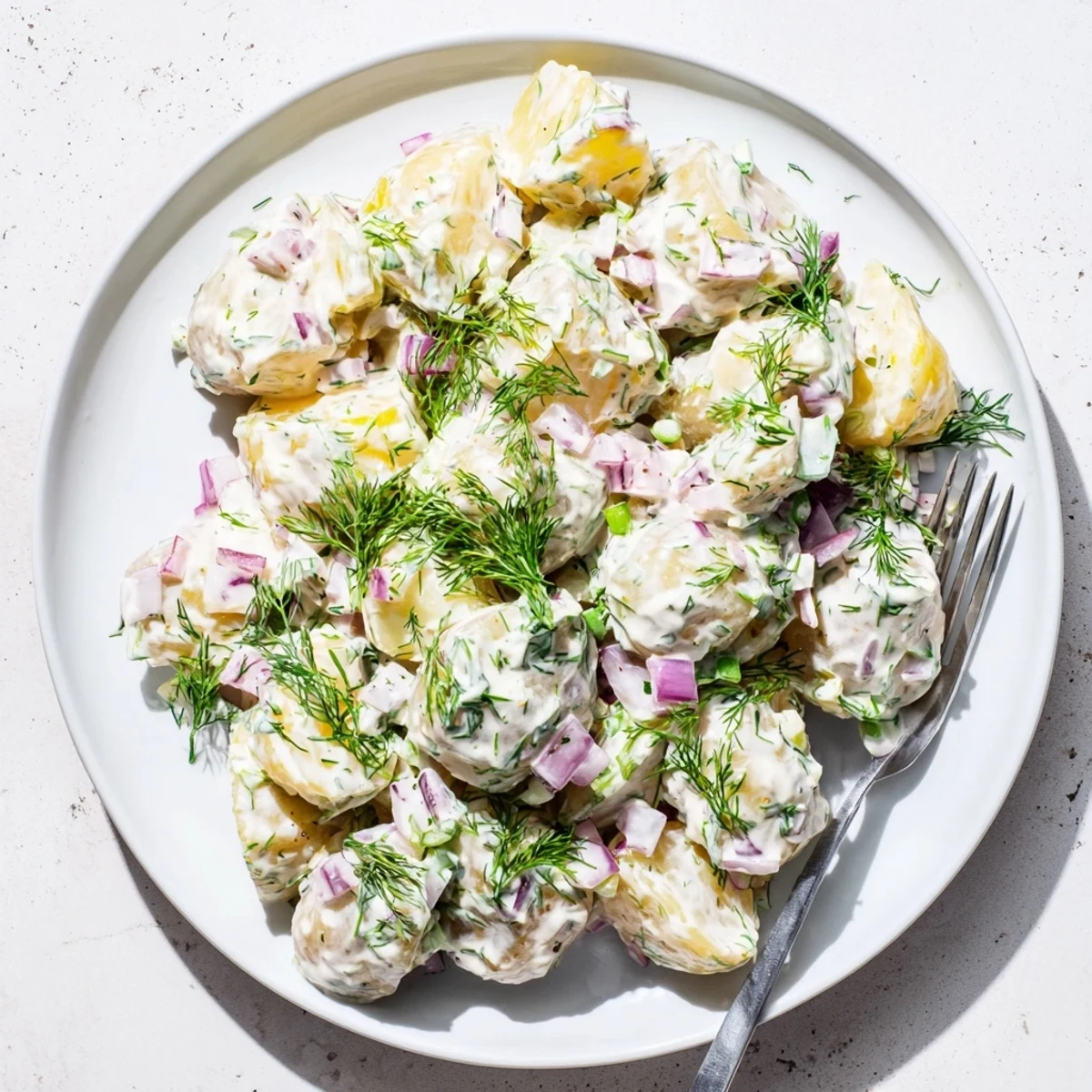 Vibrant potato salad coated in Greek yogurt dressing with diced vegetables and green herbs