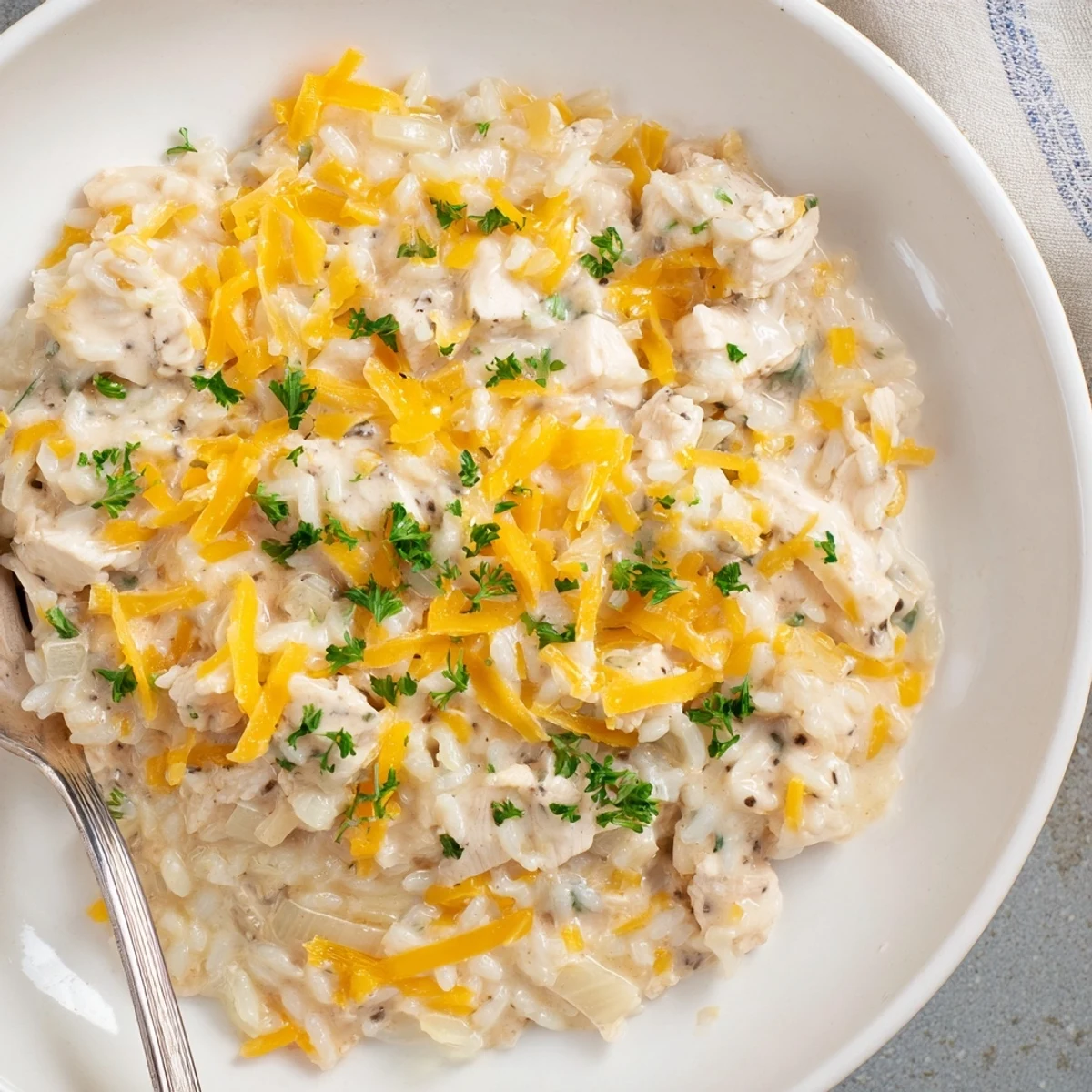 Tender chicken pieces nestled in rich creamy rice with golden cheddar topping