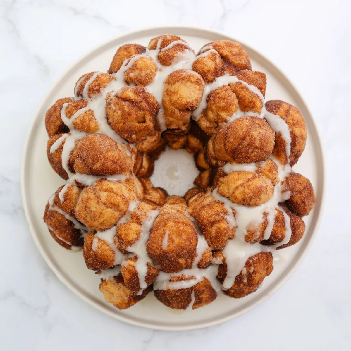 Pull-apart high protein no sugar monkey bread drizzled with vanilla glaze on serving plate