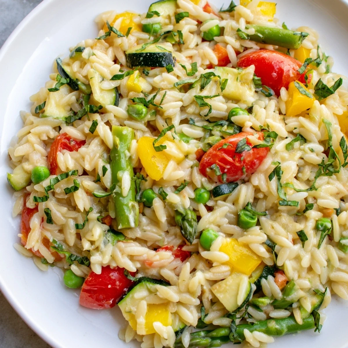 Bowl of Orzo Primavera gleaming with tender asparagus, peas, and Parmesan cheese