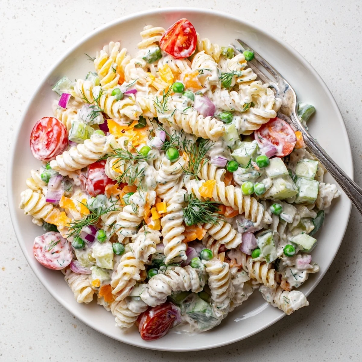 Creamy ranch pasta salad loaded with colorful crisp vegetables and tender rotini in a herb-flecked white dressing