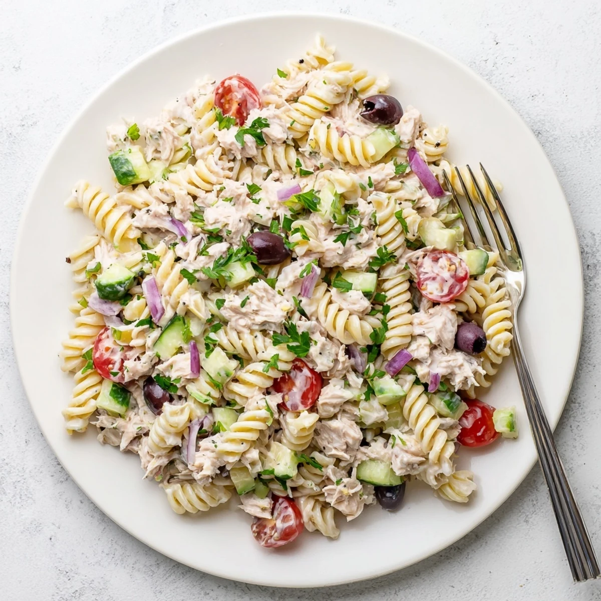 Tuna pasta salad featuring tender noodles, flaky fish, and crisp veggies in mayo dressing