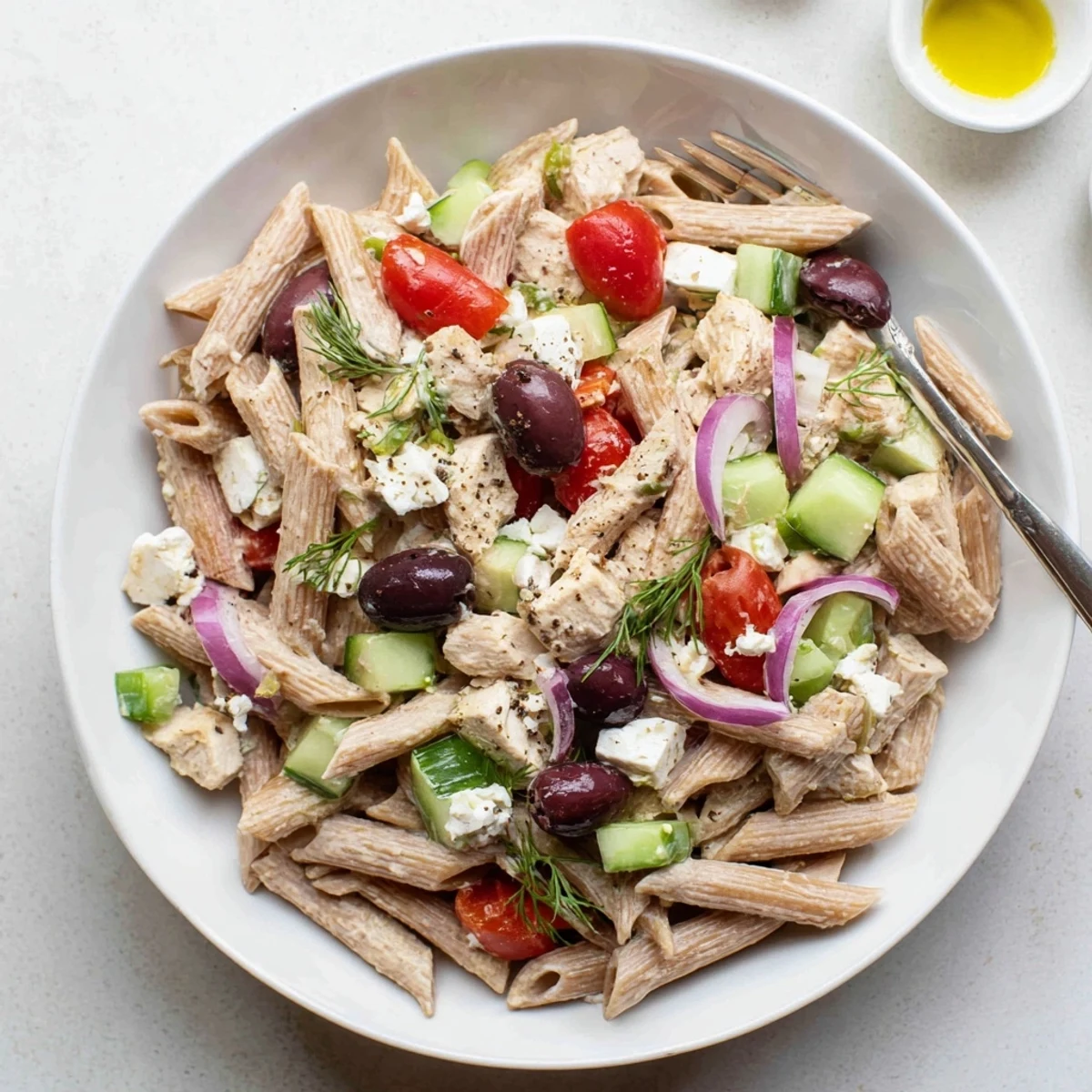 Colorful High Protein Greek Pasta Salad in a bowl with cherry tomatoes cucumber and feta