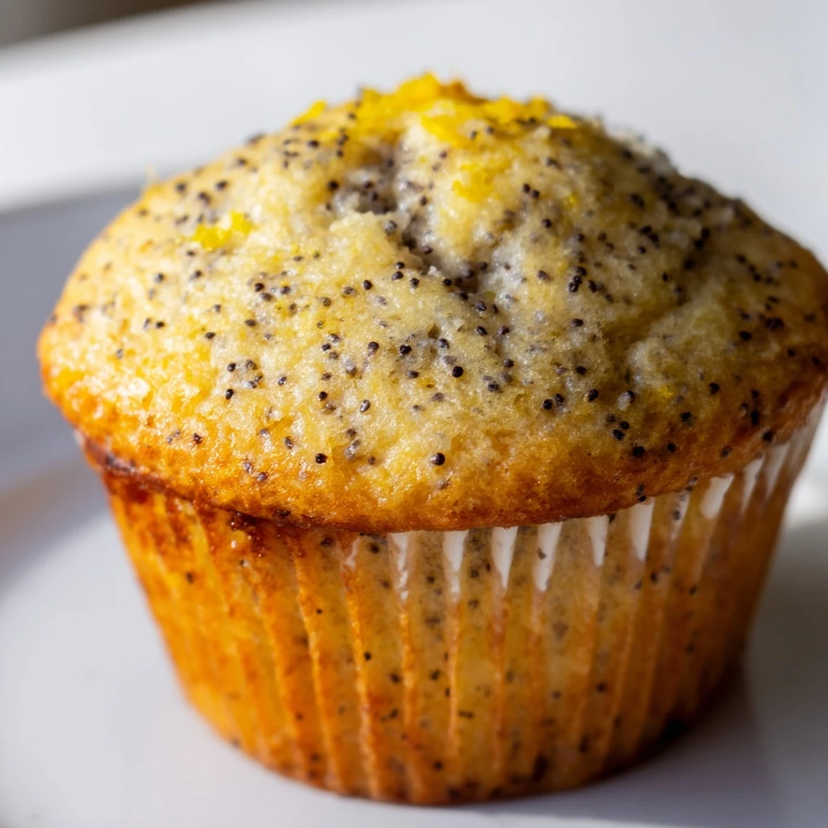 Golden lemon poppy seed muffins topped with sweet glaze on a rustic white serving plate