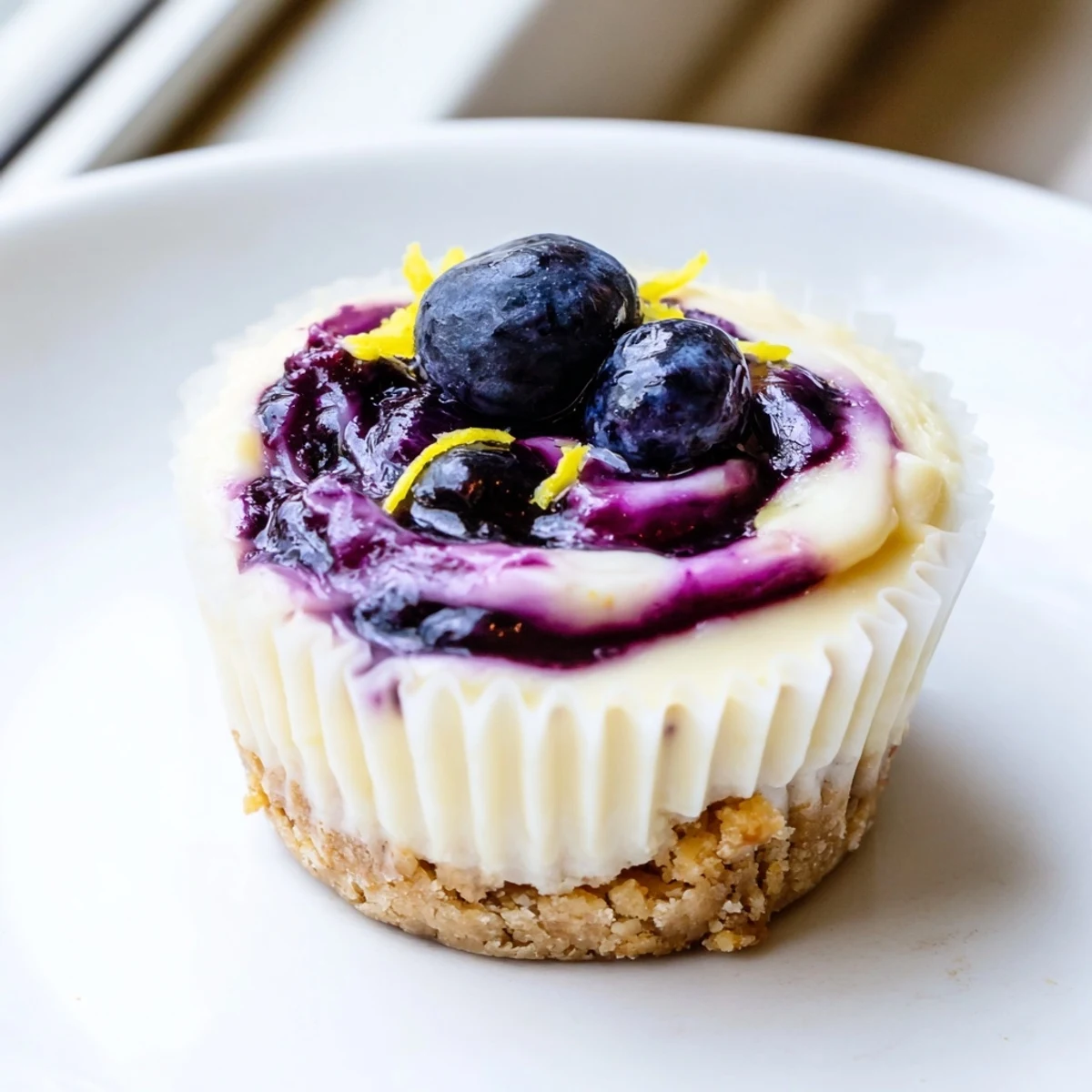Golden mini lemon blueberry cheesecakes with swirled compote on graham crusts