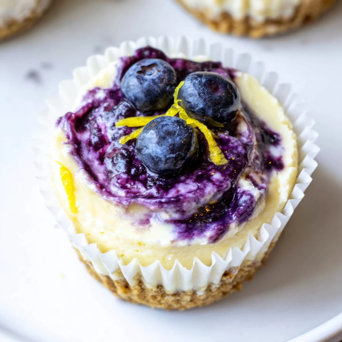 Creamy mini lemon blueberry cheesecakes topped with fresh berries and zest
