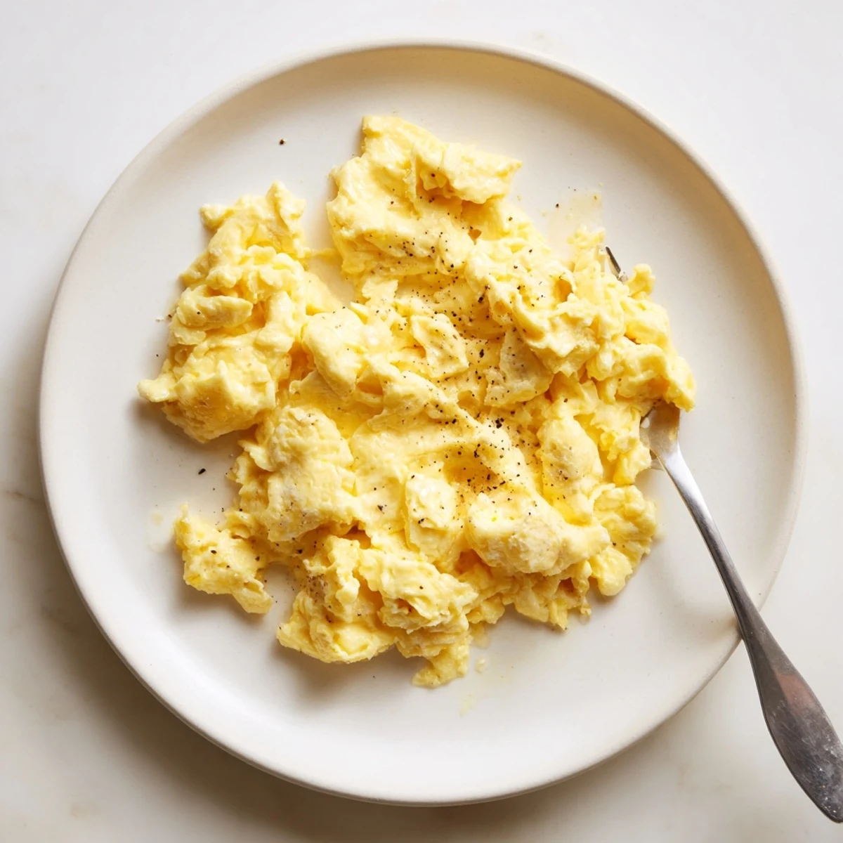 Creamy scrambled eggs with soft golden curds piled on a warm breakfast plate