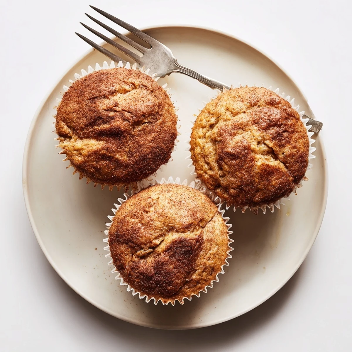 Moist banana muffins nestled in paper liners dusted with cinnamon sugar