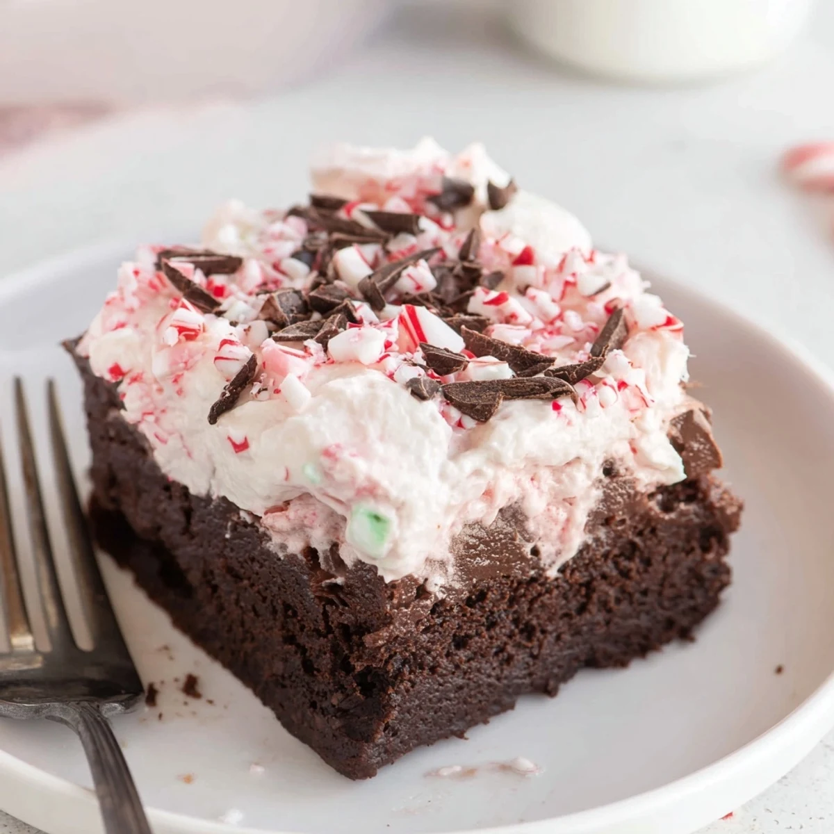 Peppermint Poke Cake chilled with whipped topping, crushed candies glistening
