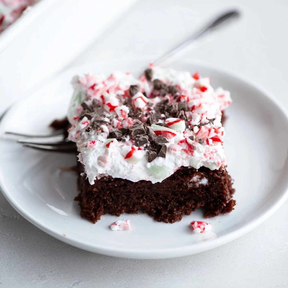 Slice of Peppermint Poke Cake showing pudding-filled holes and minty crumbs