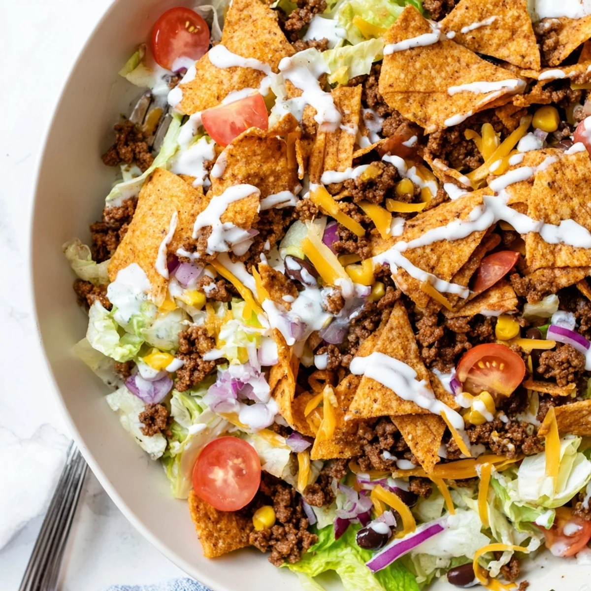 Bowl of Simple Doritos Taco Salad topped with shredded cheddar, fresh tomatoes