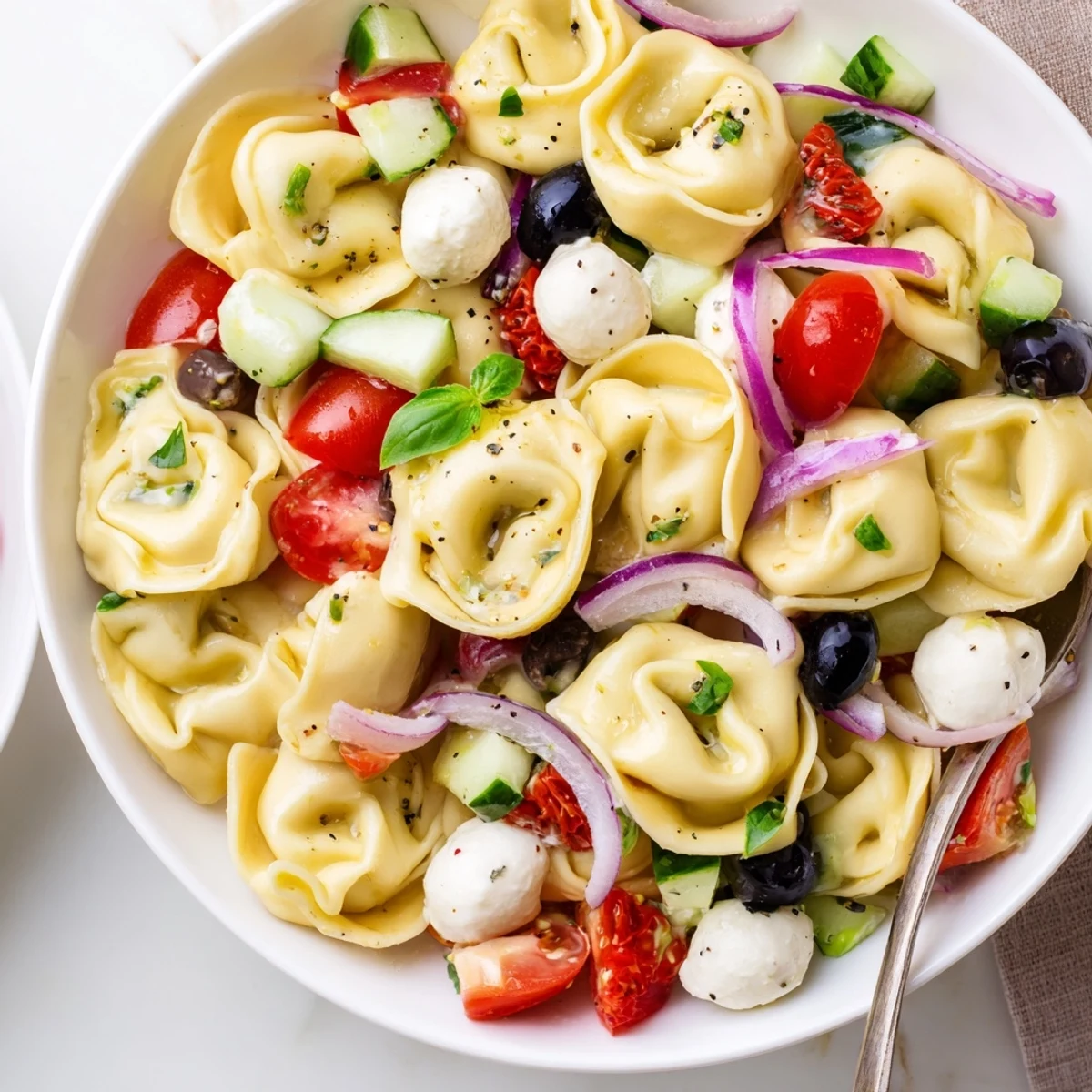 Colorful Tortellini Pasta Salad layered with mozzarella, cucumbers, and crunchy peppers