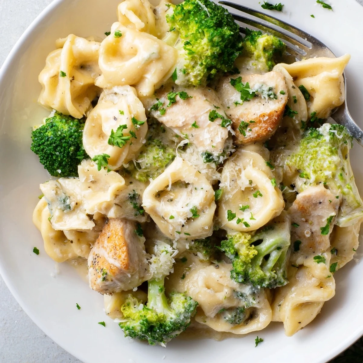 Weeknight Creamy Garlic Parmesan Tortellini Chicken Broccoli Recipe tossed in silky sauce, garnished parsley