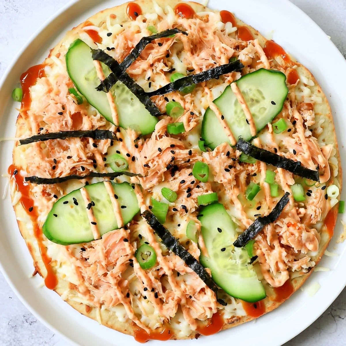 Golden baked salmon sushi flatbread pizza topped with fresh avocado and spicy sriracha drizzle