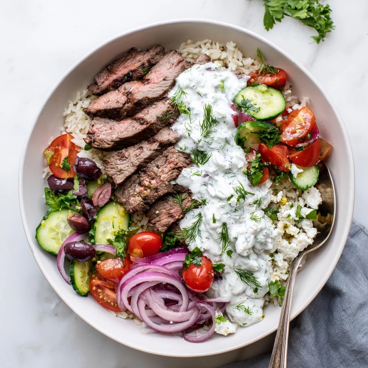 Mediterranean steak bowl featuring grilled sirloin slices over lemon-herb rice with crisp vegetables and tangy feta