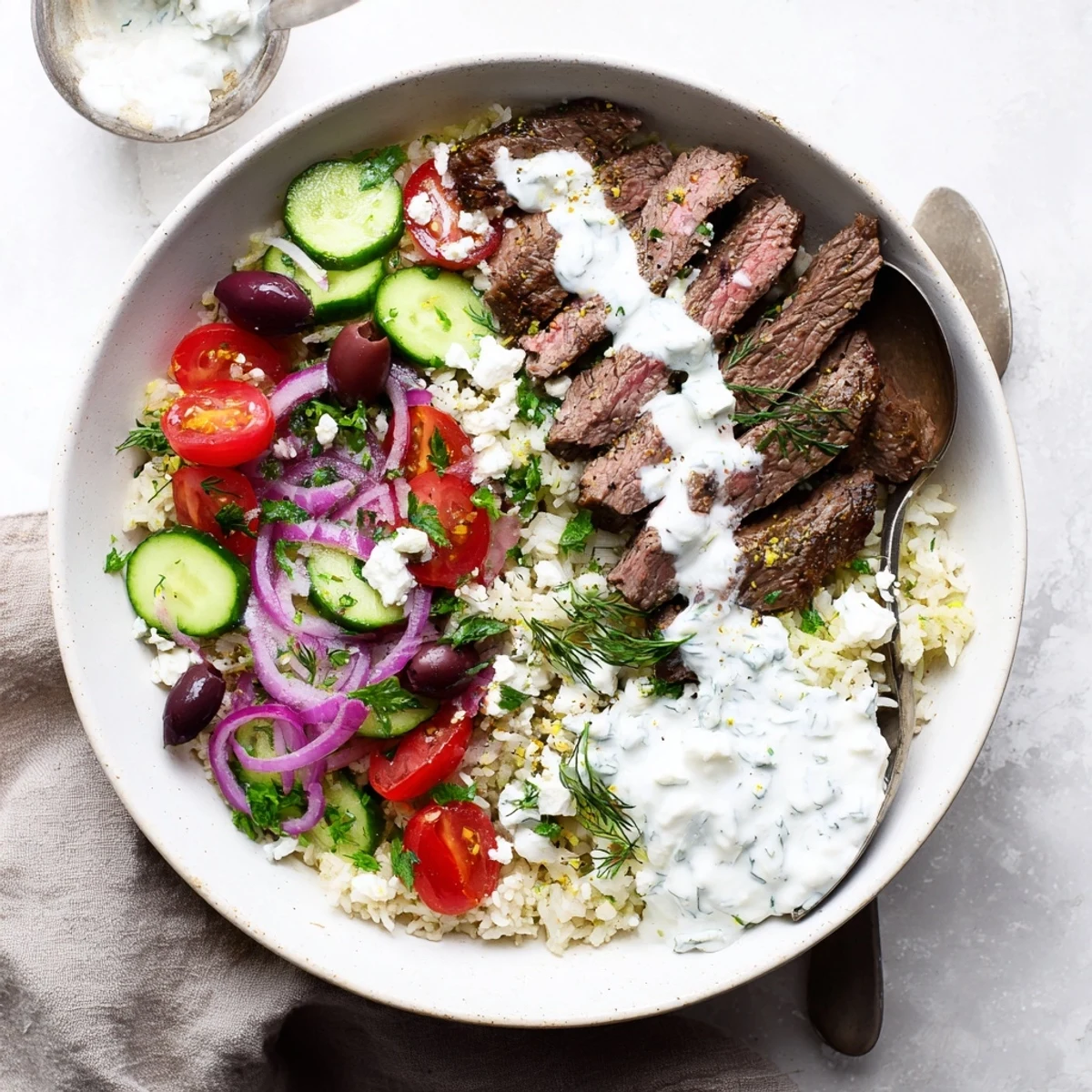 Protein-rich Mediterranean steak bowl displaying marinated grilled beef atop fluffy rice with colorful Mediterranean toppings