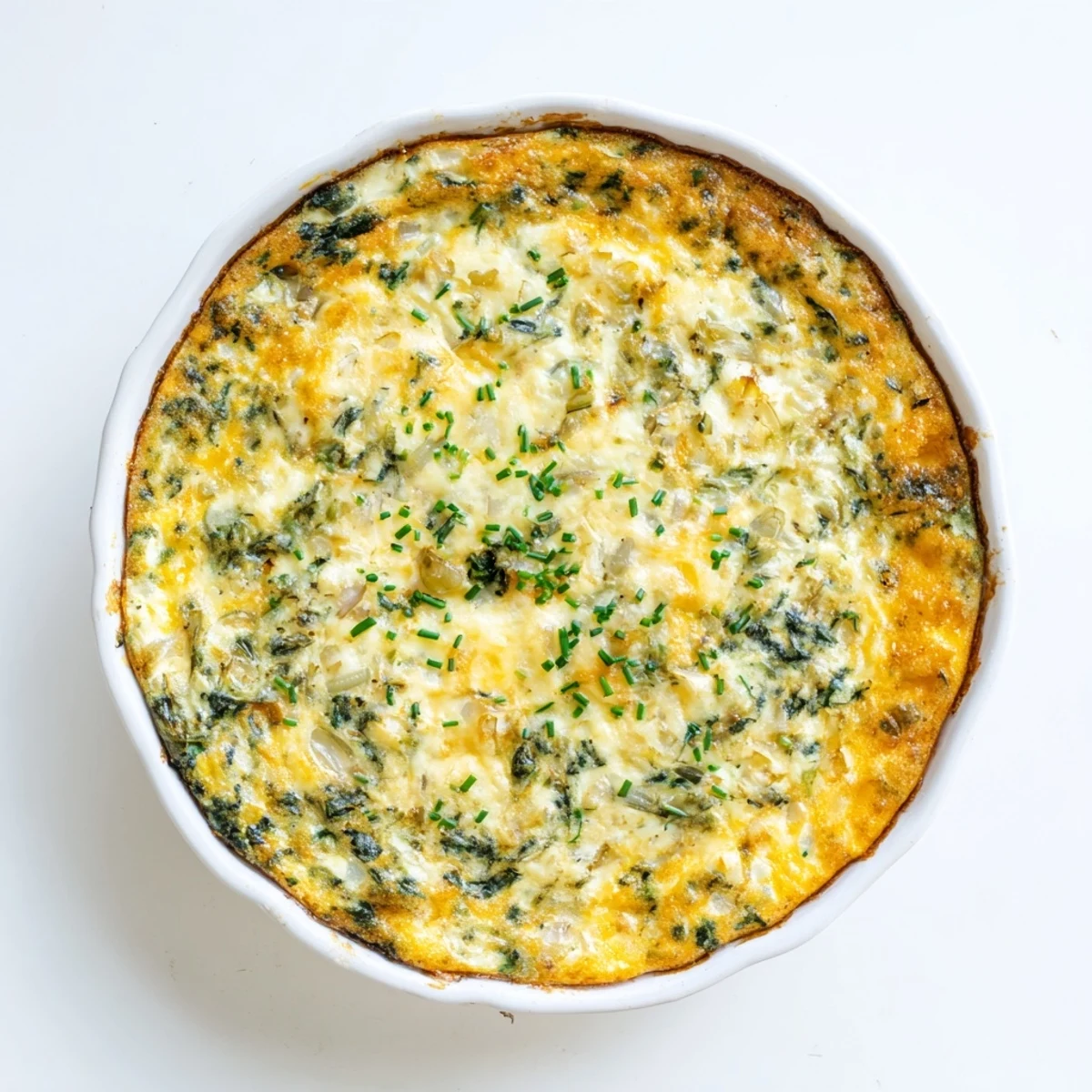 Golden baked cottage cheese spinach quiche slices served on a white plate with fresh chive garnish