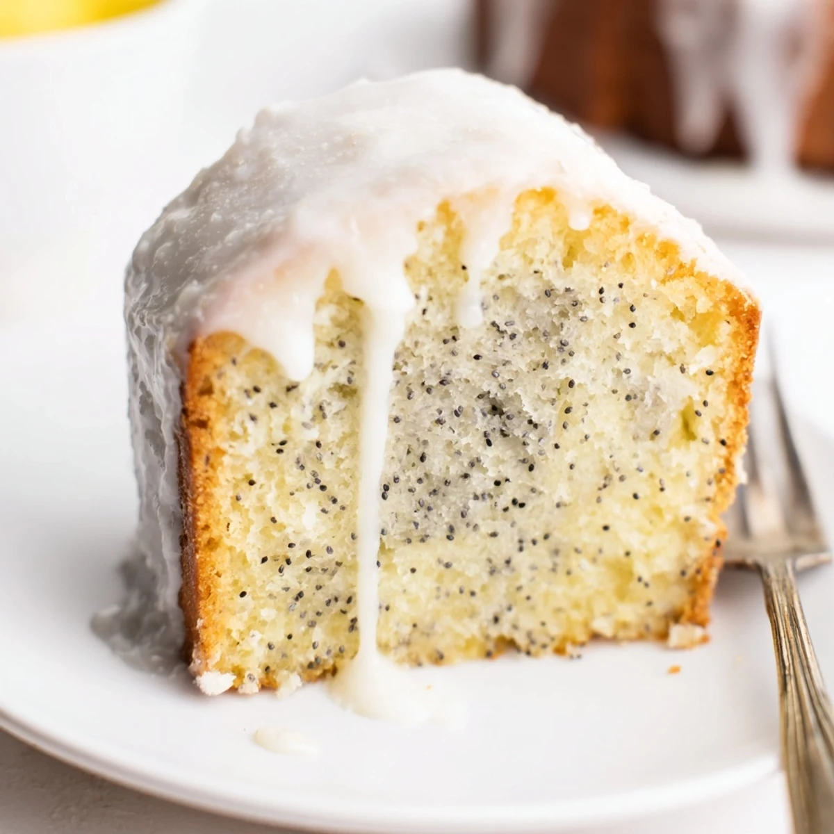 Golden lemon poppy seed loaf drizzled with white glaze on a wooden board