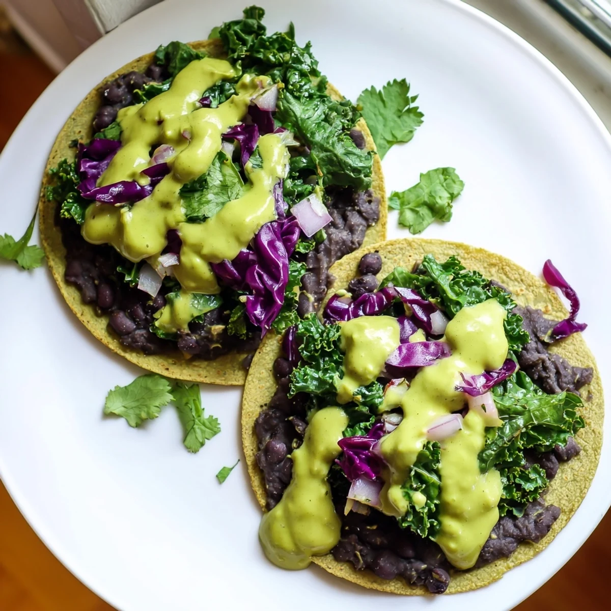 Warm corn tortillas filled with smoky black bean kale tacos drizzled with creamy green sauce