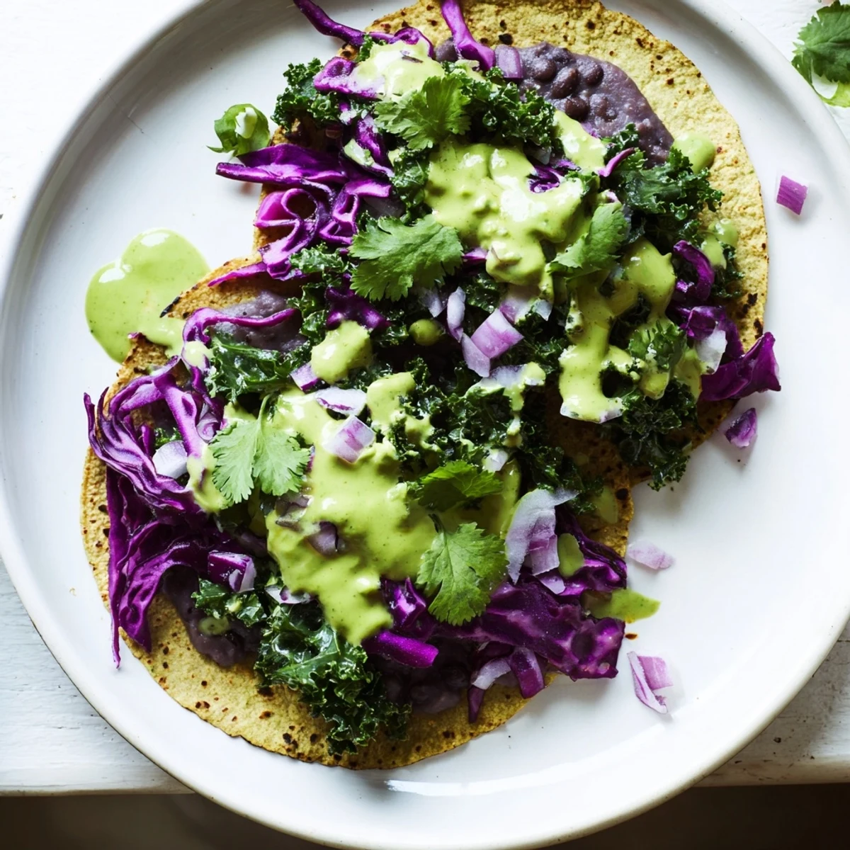 Smoky black bean kale tacos topped with vibrant sautéed greens and rich avocado sauce