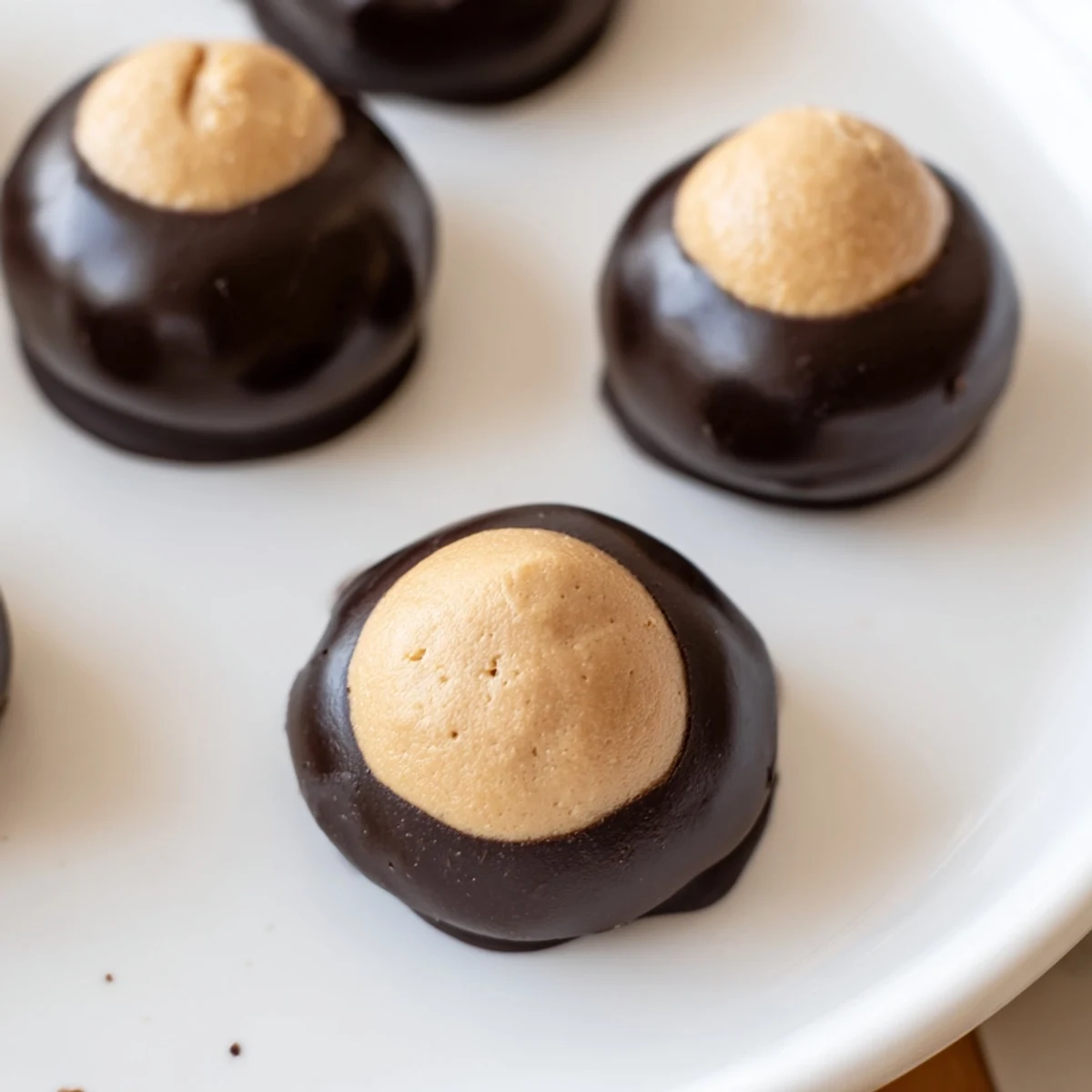 Buckeye Cookies with glossy chocolate dipping and creamy peanut butter filling on parchment
