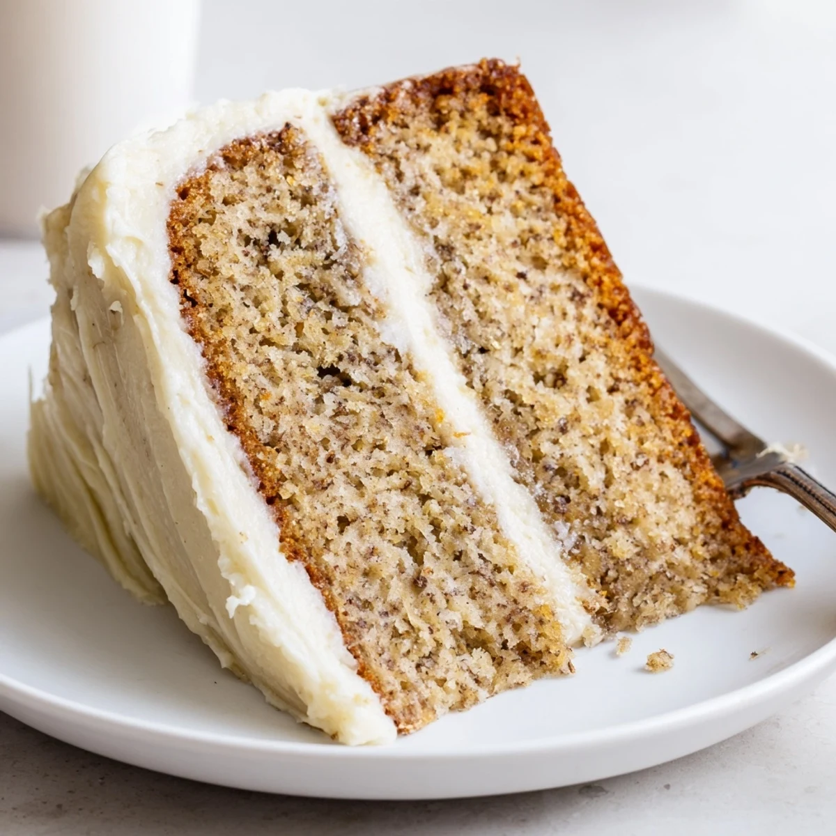 Brown butter banana cake topped with pillowy cream cheese frosting served on a white platter