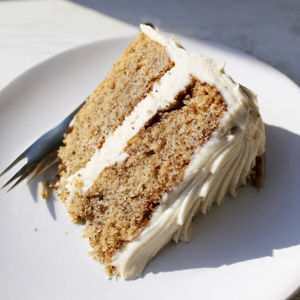 A decadent brown butter banana cake sliced to reveal moist crumbs and velvety cream cheese frosting