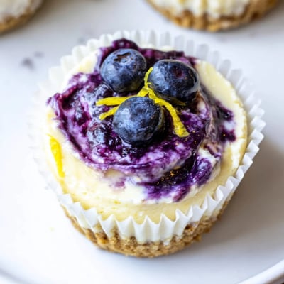 Creamy mini lemon blueberry cheesecakes topped with fresh berries and zest