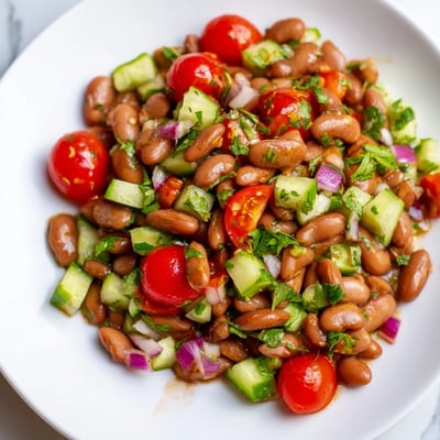 Creamy pinto beans mixed with bright tomatoes and cilantro in a rustic bowl