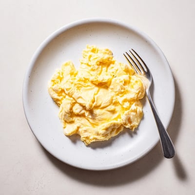 Fluffy scrambled eggs gently folded with melted butter in a nonstick skillet