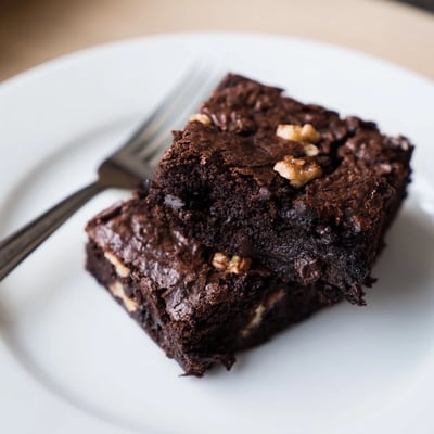 Rich dark chocolate brownies served warm with a dusting of cocoa powder